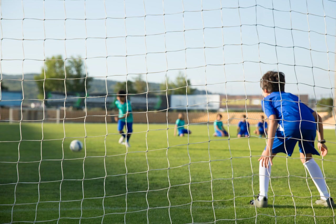 Children playing soccer taken from behind net